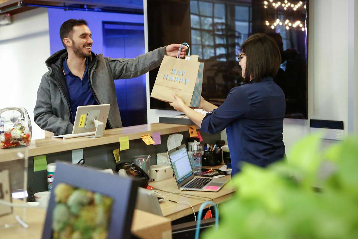 David Santana hands Itzel Cortes her order from Mendocino Farms that they placed using Ritual, an app for coworkers to order lunch together and have one person pick it up, on Thursday, February 7, 2019 in Bernal Heights San Francisco, Calif.