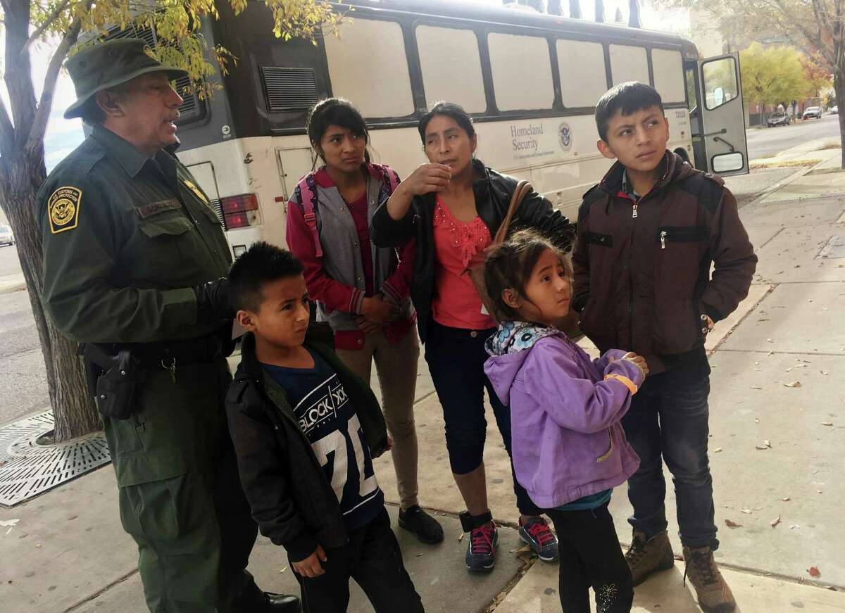 In this Thursday, Nov. 29, 2018 photo, a migrant family from Central America waits outside the Annunciation House shelter in El Paso, Texas, after a U.S. Immigration and Customs Enforcement officer drops them off. Volunteer shelters along the U.S.-Mexico border say they are preparing for an expected surged of new immigrants seeking asylum in the U.S. who will need temporary housing as the holidays approach. (AP Photo/Russell Contreras)