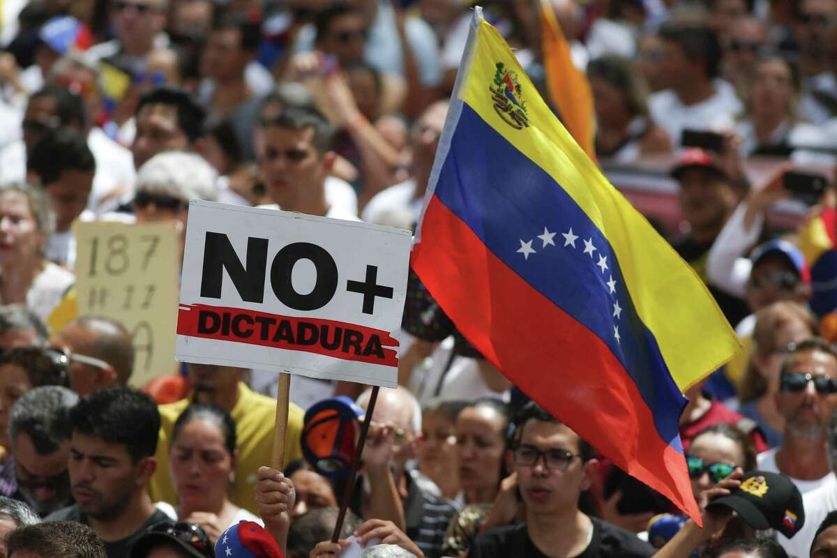 Anti-government protesters rally to demand the resignation of Venezuelan President Nicolas Maduro, as one holds a sign that reads in Spanish "No more dictatorship" in Caracas, Venezuela, Monday, March 4, 2019.
