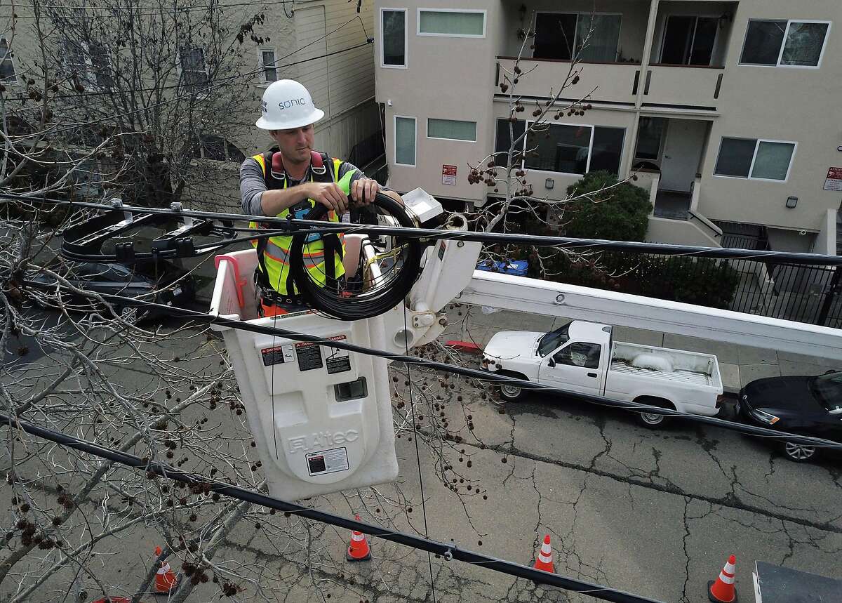 Sonic technician Tom Sherrill works on securing the cable to the utility wires through branches as he installs fiber optic cable to a home in Berkeley, Calif., on Monday, March 4, 2019. Sonic is expanding in the East Bay, and fiber lines are being run directly to customers' homes throughout Berkeley and Oakland .