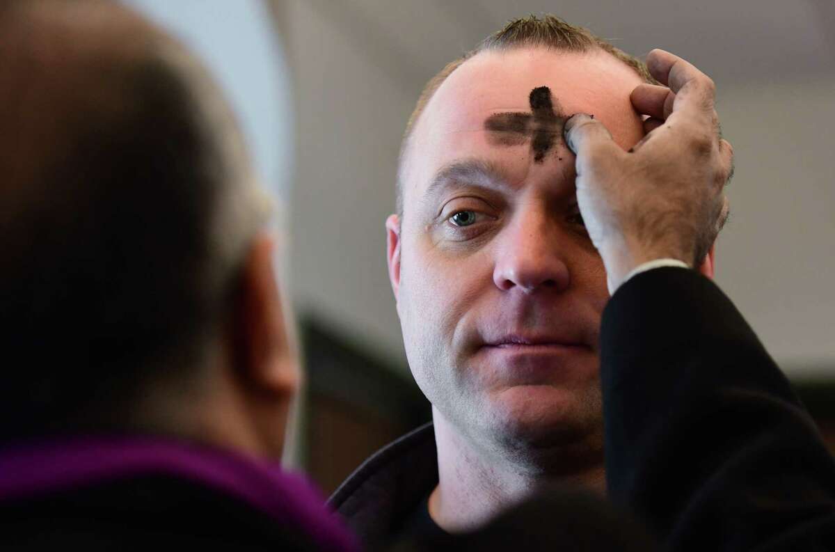 Fr. Tomi Thomas administers ashes to firefighter Tom Reich Wednesday, March 6, 2019, as St. Matthews Church satellite bus delivers Ash Wednesday Services to locations including the Norwalk Fire Department Headquarters in Norwalk, Conn.
