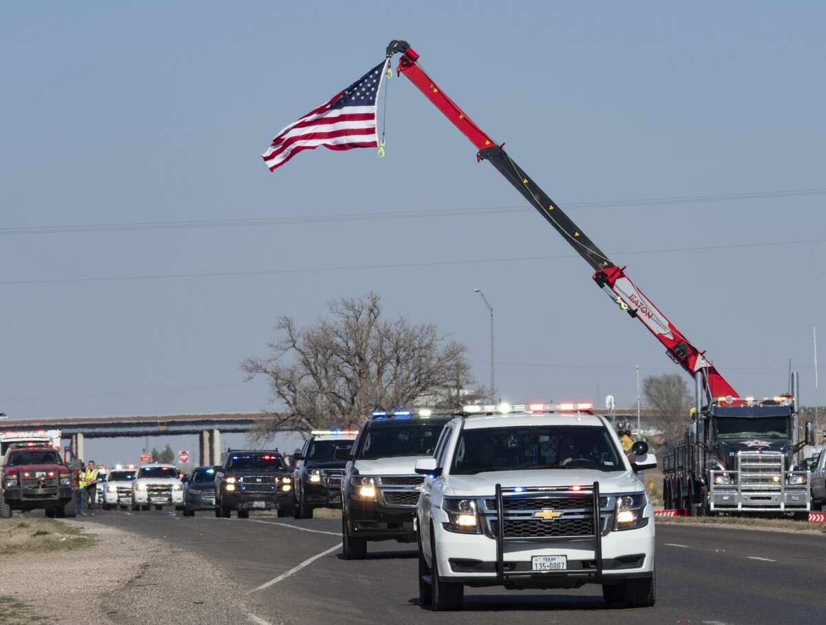 Area and state police escort the body of MPD Officer Nathan Heidelberg back to Midland 03/06/2019 as they make their way from I-20 to drive north up Loop 250 under the American Flag hung from an area wrecker boom. Tim Fischer/Reporter-Telegram