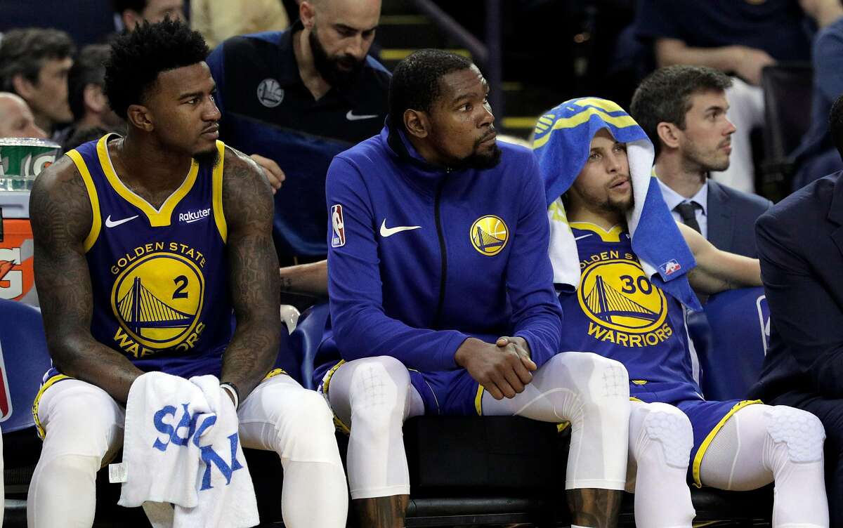 Jordan Bell (2), Kevin Durant (35) and Stephen Curry (30) watch from the bench as the Celtics pull away in the second half as the Golden State Warriors played the Boston Celtics at Oracle Arena in Oakland, Calif., on Tuesday, March 5, 2019.
