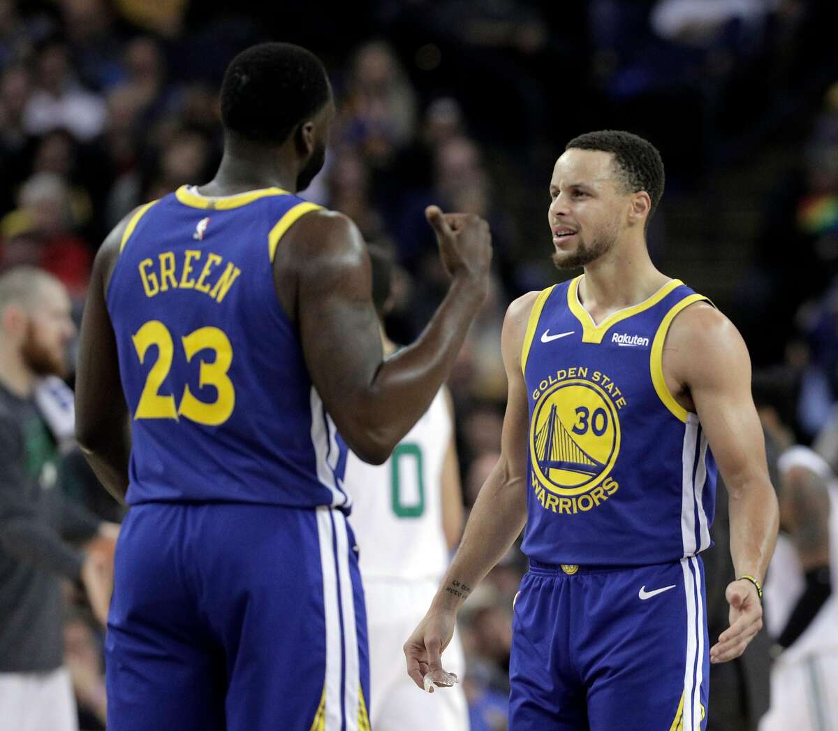 Stephen Curry (30) talks to Draymond Green (23) after Green was called for a questionable foul and argued with the official in the first half as the Golden State Warriors played the Boston Celtics at Oracle Arena in Oakland, Calif., on Tuesday, March 5, 2019.