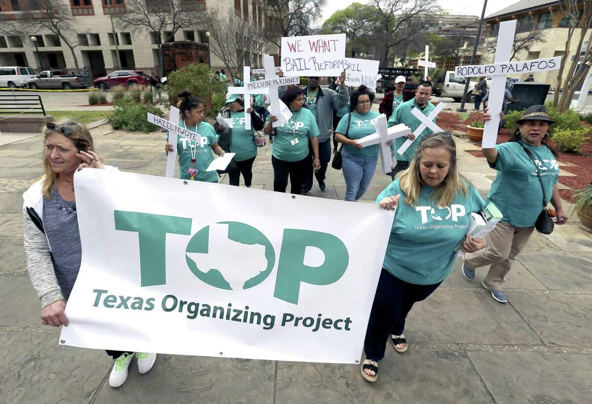 Members of the Texas Organizing Project march around the Bexar County courthouse Thursday before holding a news conference to present a petition demanding an end to the practice of cash bail in the county.