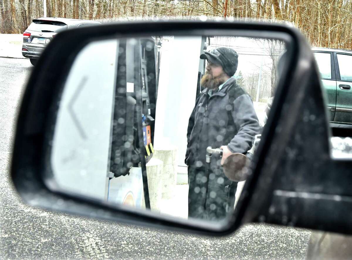 Guilford Connecticut - Wednesday February 18, 2019: Brad Lindberg, a car mechanic at the Four Corners Gas Station in Guilford puts gas into a customers automobile. The Four Corners Gas Station on Route 80 in Guilford is an old fashioned full service gas station