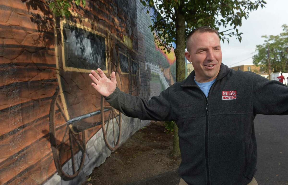 Jason Milligan, owner of Milligan Realty, stands next to the mural he had painted on his building at 97 Wall Street Friday, October 19, 2018, in Norwalk, Conn. Milligan, who remains the subject of a lawsuit after purchasing those and other properties within the stalled Wall Street Place development area.