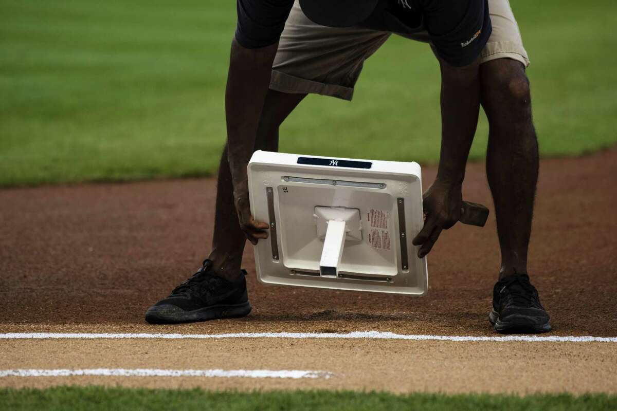 A member of the grounds crew installs first base before a game at Yankee Stadium last season. At the behest of Major League Baseball, the independent Atlantic League will try out several rule changes in the coming season, including banning pitching changes, a slightly longer distance from home plate to the mound, and even increasing the size of the bases.