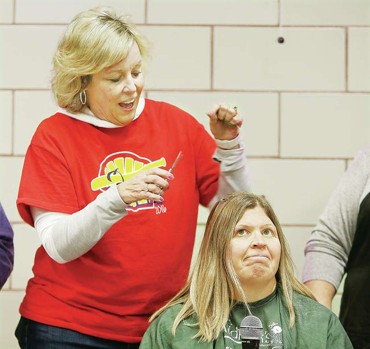 Several students and two teachers were among those that got in the first clips on Fletcher, seated, before her sister shaved her head bald. A large event will be held in St. Louis today to shave the heads of many people who have raised money for the foundation.