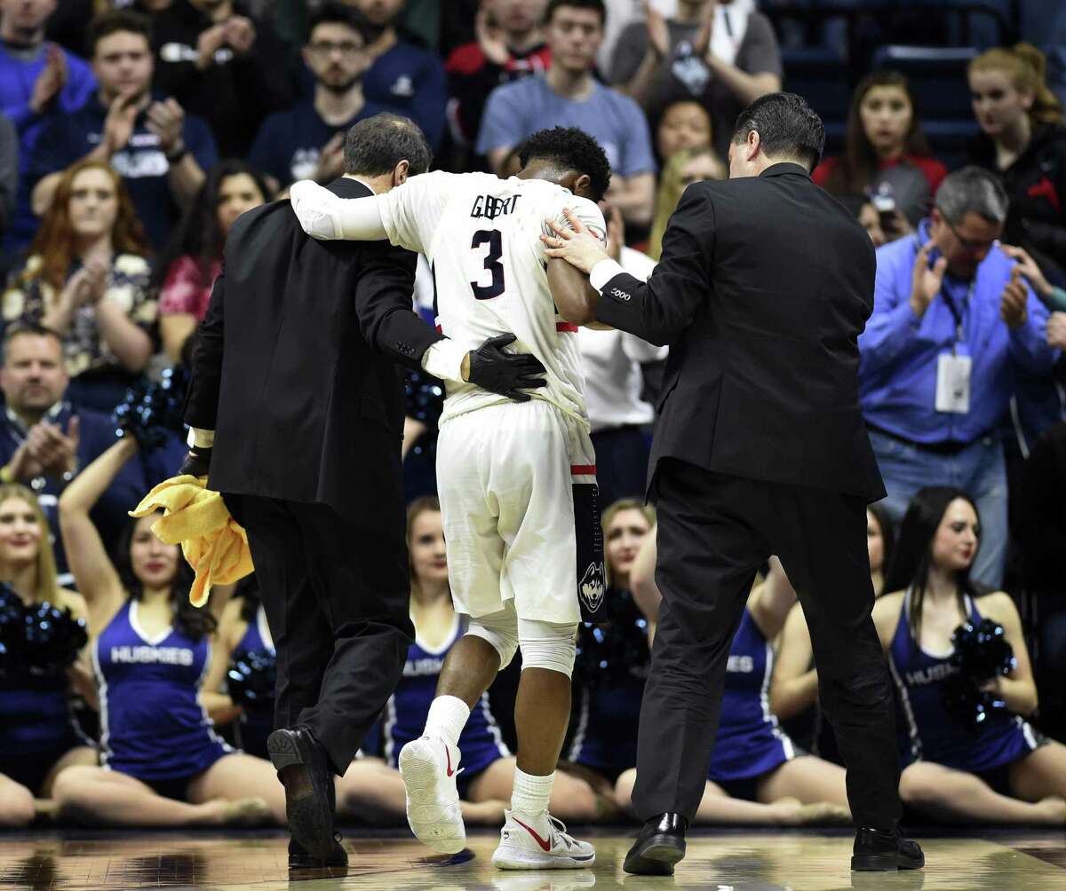 UConn’s Alterique Gilbert (3) is helped off the court after suffering a facial laceration during the second half of Thursday’s loss to Temple at Gampel Pavilion in Storrs. Gilbert’s playing status for Sunday’s regular season finale at East Carolina is uncertain.