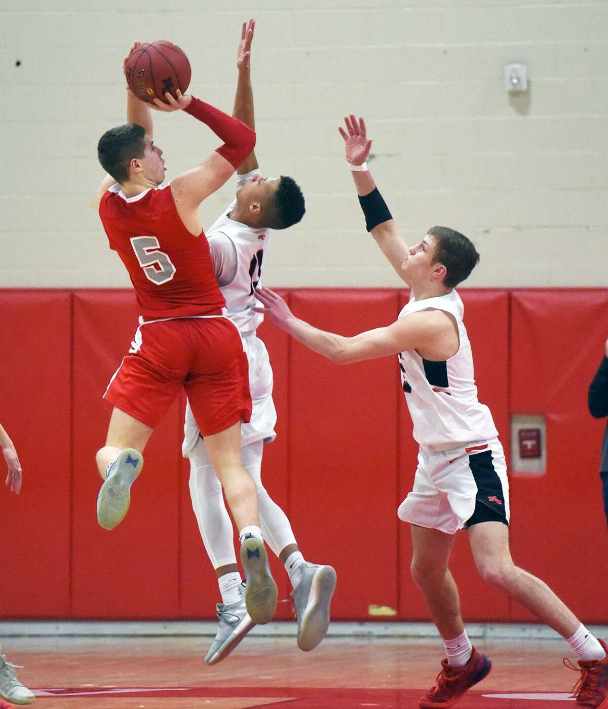 St. Bernard’s Max Lee (5) goes up for a shot as New Canaan’s Luke Rwambuya and Alex Gibbens defend during a CIAC Division IV quarterfinal game at New Canaan High School on Friday.