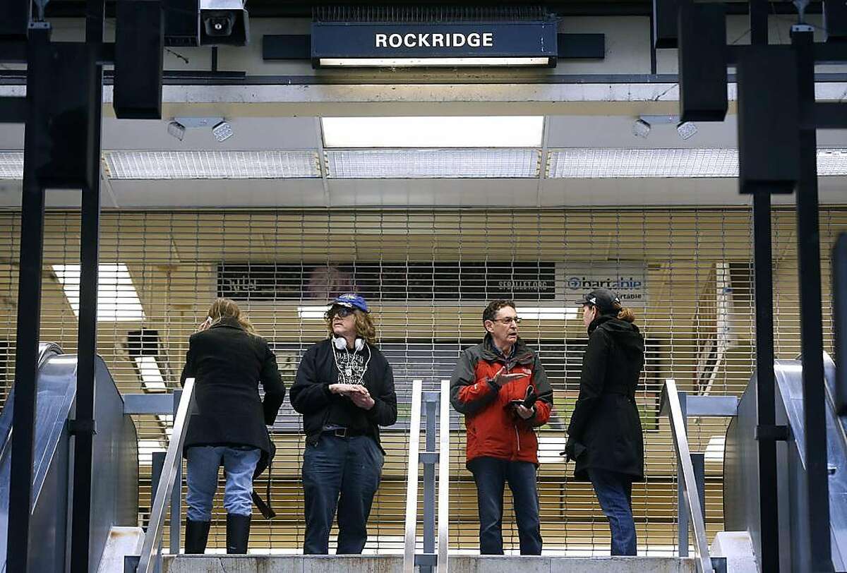 Stranded passengers stand at the entrance to the Rockridge BART station in Oakland, Calif. on Saturday, March 9, 2019 after computer glitches forced a shutdown of the entire transit system.