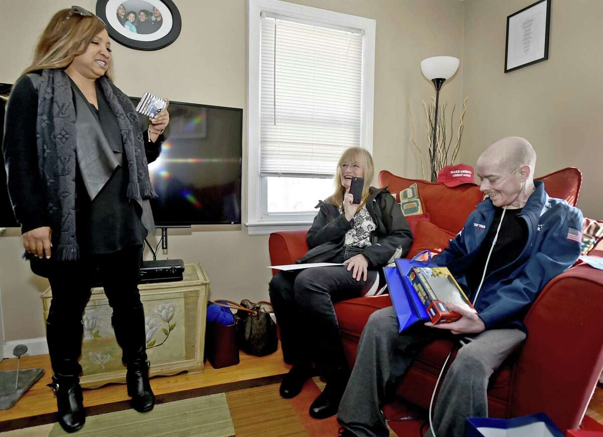 West Haven, Connecticut - Saturday, March 9, 2019: Jay W. Barrett, 44, of West Haven, terminally ill with cystic fibrosis, right, who is a President Donald Trump fan and received a phone call from the President Tuesday, holds one of many gifts he received from the President and his son Eric Trump Saturday afternoon delivered to his home by HUD official and personal Trump family friend Lynne Patton, left, who is from the New Haven area. Also visiting Barrett Saturday is West Haven Mayor Nancy R. Rossi, center.