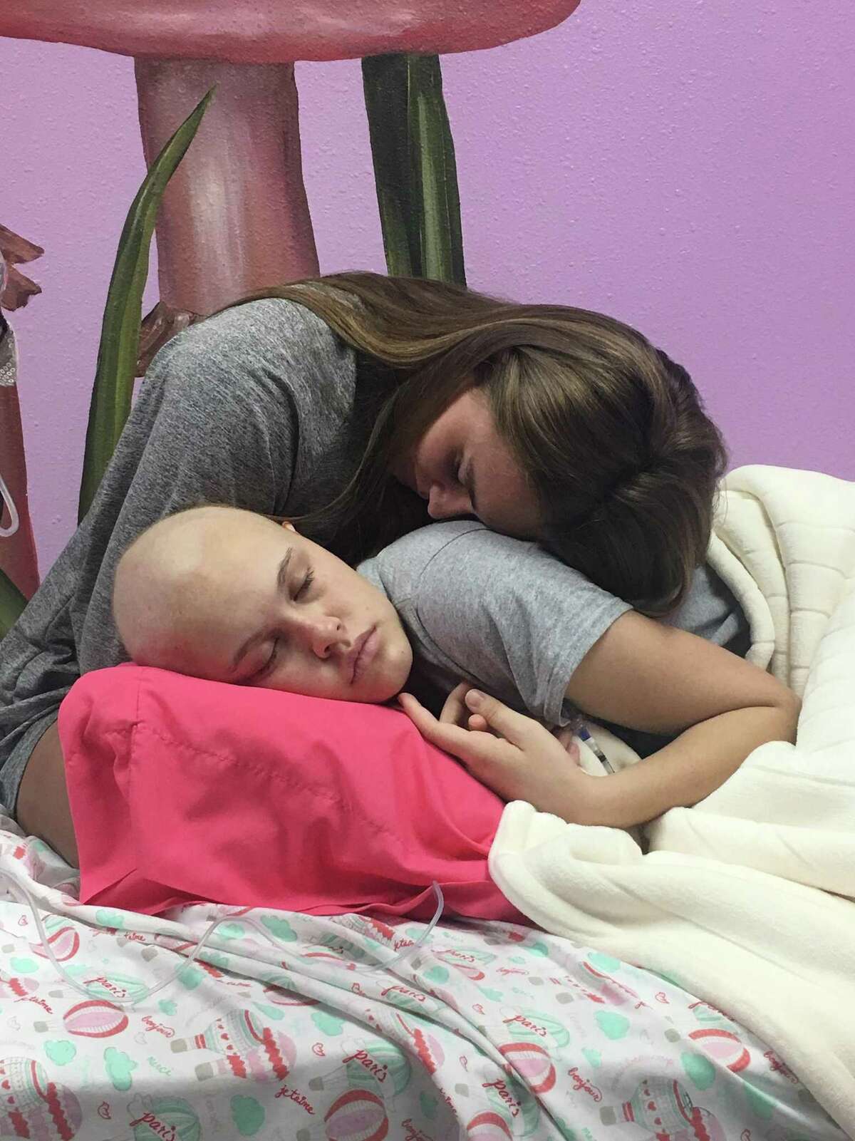 Paige Hare rests on her sister Presley as Presley goes through chemotherapy.