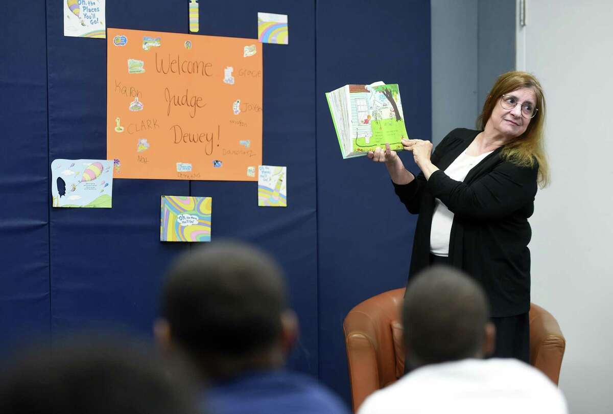 Above, Judge Julia Dewey reads “Wacky Wednesday” by Dr. Seuss to special needs students at High Road School in Wallingford on Wednesday. At right, social worker Jordana Fowlin, right, dressed for the event, listens along with the students.
