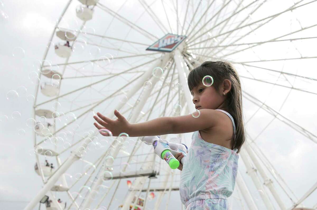 Mia Santana, 3, of Houston chases down bubbles on the midway at the Houston Livestock Show and Rodeo on Monday, March 11, 2019 in Houston.