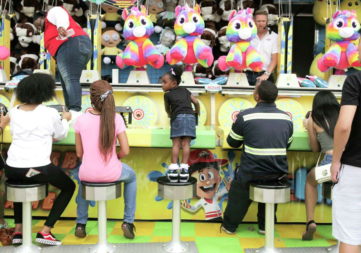 Royaltee Manuel, 3, of Houston gets a better view as she competes for a stuffed animal on the midway at the Houston Livestock Show and Rodeo on Monday, March 11, 2019 in Houston.
