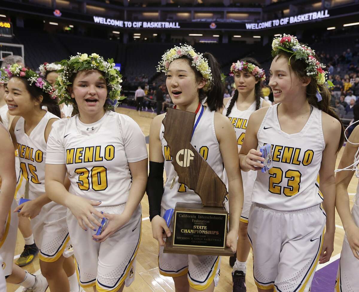 Menlo School's Avery Lee, center, carries the championship trophy received for defeating Rolling Hills Prep 70-63 in the CIF girls' Division II state high school basketball championship game, Saturday, March 9, 2019, in Sacramento, Calif. (AP Photo/Rich Pedroncelli)