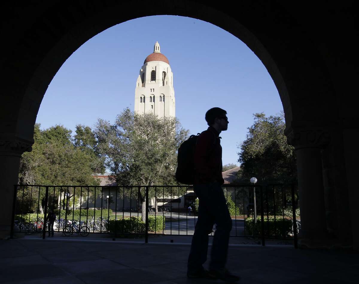 FILE - In this Feb. 15, 2012 file photo, a Stanford University student walks in front of Hoover Tower on the Stanford University campus in Palo Alto, Calif. Federal authorities have charged college coaches and others in a sweeping admissions bribery case in federal court. The racketeering conspiracy charges were unsealed Tuesday, March 12, 2019, against coaches at schools including Stanford, Wake Forest, Georgetown, the University of Southern California and the University of Southern California and University of California, Los Angeles. (AP Photo/Paul Sakuma, File)