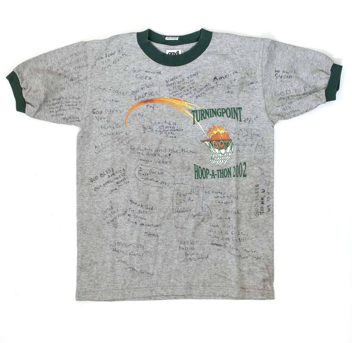 Keep clicking to see iconic T-shirts from the State Museum collection. "Turningpoint Hoop-a-thon, 2002." Collected following 9/11 from the memorial fence at Cedar and Broadway in Manhattan. The State Museum collected memorial materials from several locations in New York City, and many of those memorials include T-shirts, often signed.