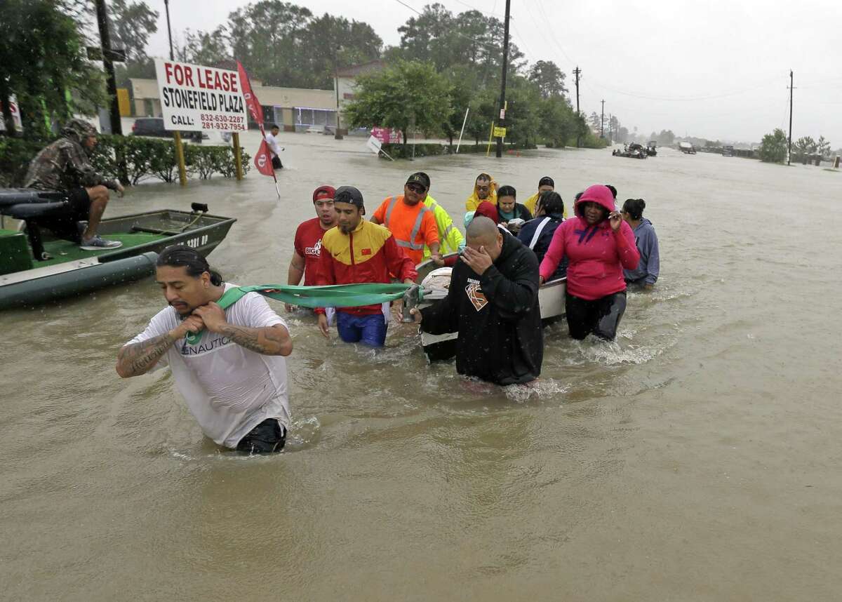 In this Aug. 28, 2017, file photo, evacuees wade down Tidwell Road as floodwaters from Tropical Storm Harvey rose in Houston.