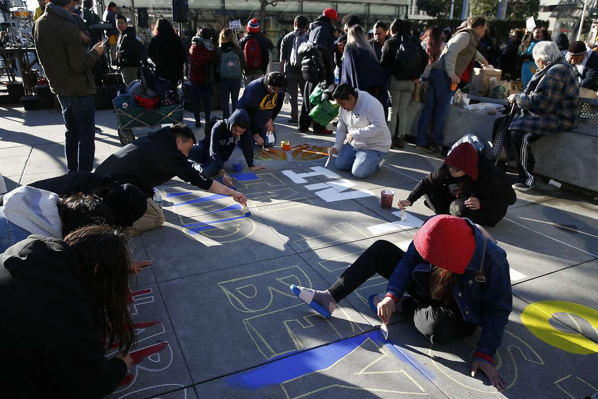 Protesters paint messages on the sidewalk across the street from the James R. Browning United States Courthouse where the 9th Circuit Court of Appeals hears arguments in President Trump's lawsuit against California's sanctuary law that protects immigrants in San Francisco, Calif. on Wednesday, March 13, 2019.