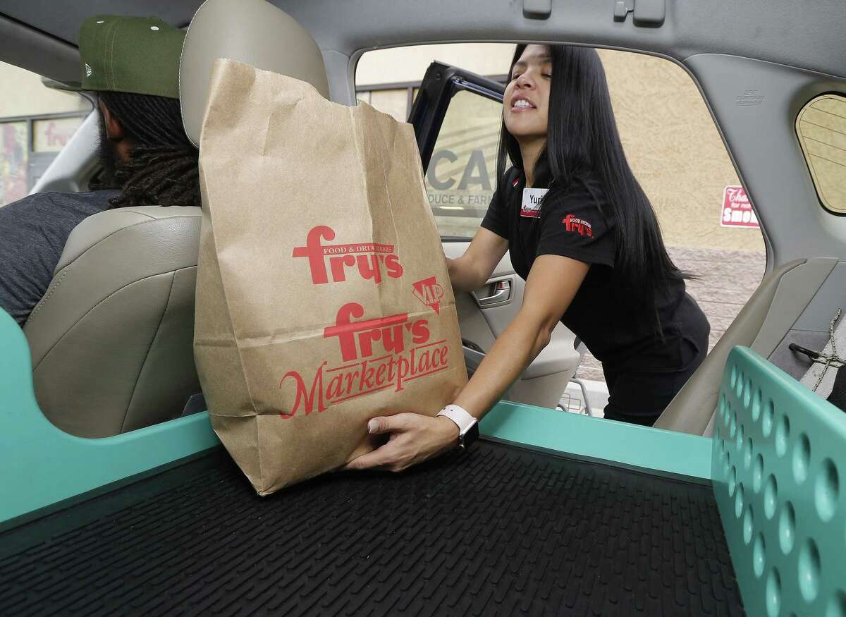 Fry’s customer service representative Yuri Alvarado puts groceries into the self-driving Nuro vehicle parked outside a Fry’s supermarket, which is owned by Kroger, as part of a pilot program for grocery deliveries on Aug. 16, 2018, in Scottsdale, Ariz. Kroger announced Wednesday it would start automated deliveries at two stores in Houston.