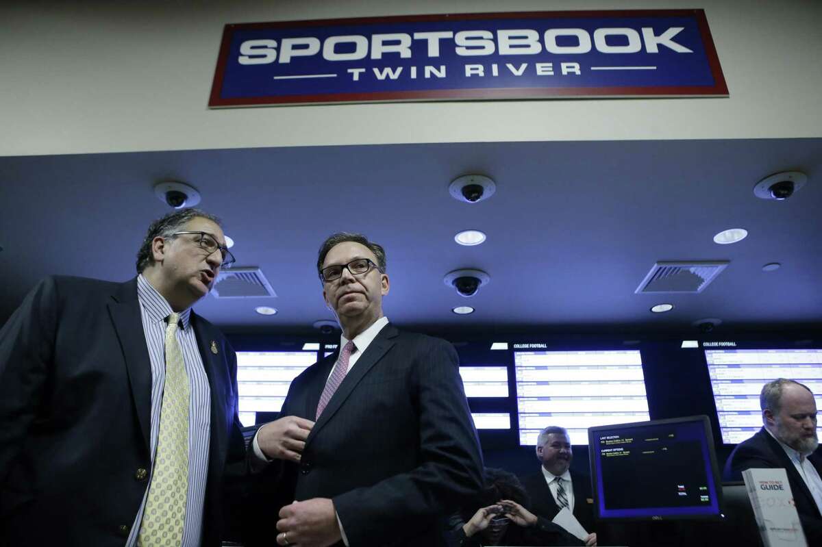 Twin River Casino Hotel Vice President and General Manager Craig Sculos, left, and John Taylor, chairman of Twin River Worldwide Holdings, second from left, prepare to face reporters before a ceremony on the first day of sports betting, Monday, Nov. 26, 2018, at Twin River Casino Hotel, in Lincoln, R.I. Rhode Island is the first New England state to legalize sports betting since the U.S. Supreme Court struck down a federal law this year that made most sports gambling illegal. (AP Photo/Steven Senne)