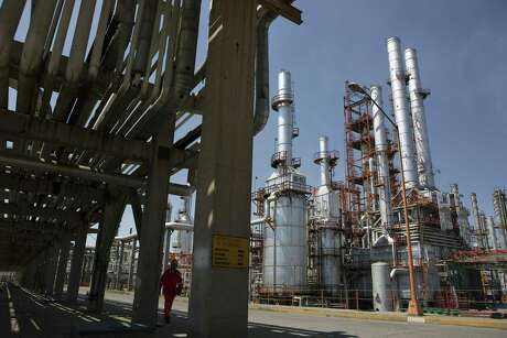 A worker walks under a road of pipelines at the Petroleos Mexicanos Miguel Hidalgo oil refinery in Tula de Allende, Mexico, on Thursday, March. 6, 2013. Susana Gonzalez /Bloomberg