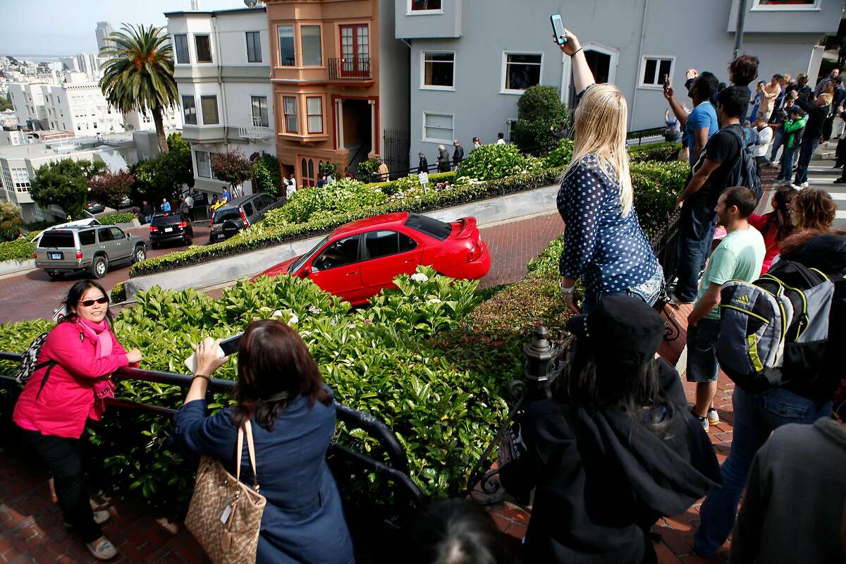 Tourists take pictures from the top of Lombard St. at Hyde St. in San Francisco, CA, Saturday May 17, 2014. Due to neighbor complaints of overcrowding, the SFMTA is proposing a pilot program that would shut down Lombard St. from Larkin to Leavenworth, for four weekends in the height of the summer tourist season.