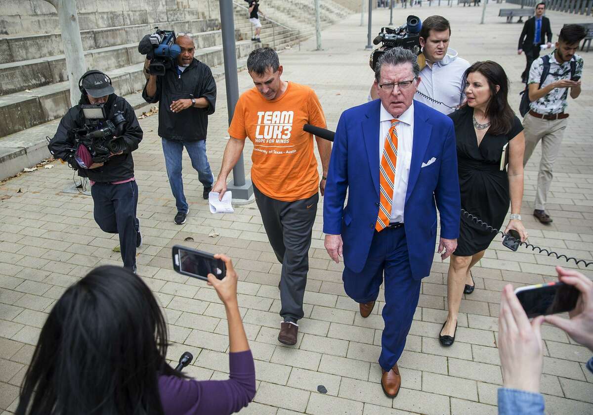 Texas men's tennis coach Michael Center, center left, walks with Defense lawyer Dan Cogdell, center right, away from the United States Federal Courthouse in Austin, Texas, Tuesday, March 12, 2019. Center is among a few people in the state charged in a scheme that involved wealthy parents bribing college coaches and others to gain admissions for their children at top schools, federal prosecutors said Tuesday. (Ricardo B. Brazziell