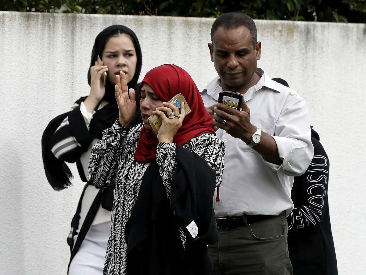 People wait outside a mosque in central Christchurch, New Zealand, Friday, March 15, 2019. Many people were killed in a mass shooting at a mosque in the New Zealand city of Christchurch on Friday, a witness said. Police have not yet described the scale of the shooting but urged people in central Christchurch to stay indoors. (AP Photo/Mark Baker)