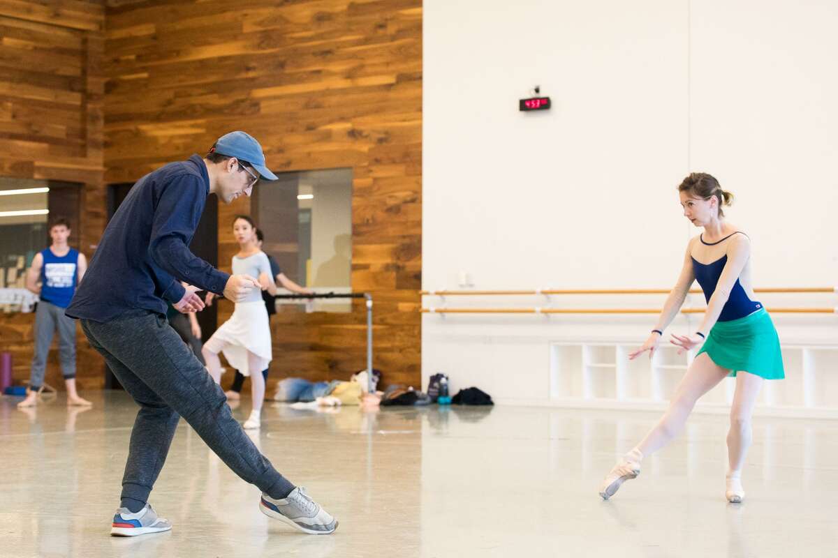 Choreographer Justin Peck demonstrates a move for principal dancer Melody Mennite and other artists of Houston Ballet during rehearsals for the world premiere of his new work "Reflections."