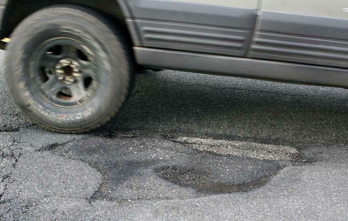 A vehicle passes by a pothole along Anderson Ave in Milford Conn., on Friday Mar. 16, 2018.