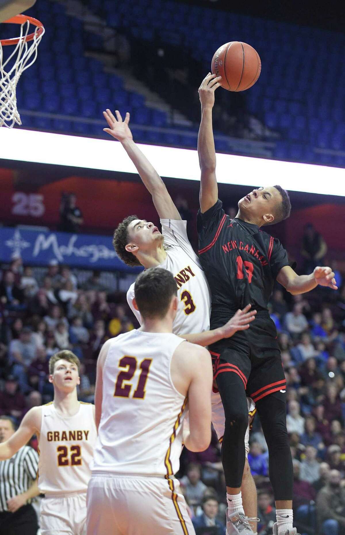 New Canaan’s Luke Rwambuya (13) finger rolls a shot against Gramby’s Elliyas Delaire (3) in the second half of the CIAC Division IV finals at Mohegan Sun Arena in Uncasville on Saturday. New Canaan defeated Gramby 55-39.