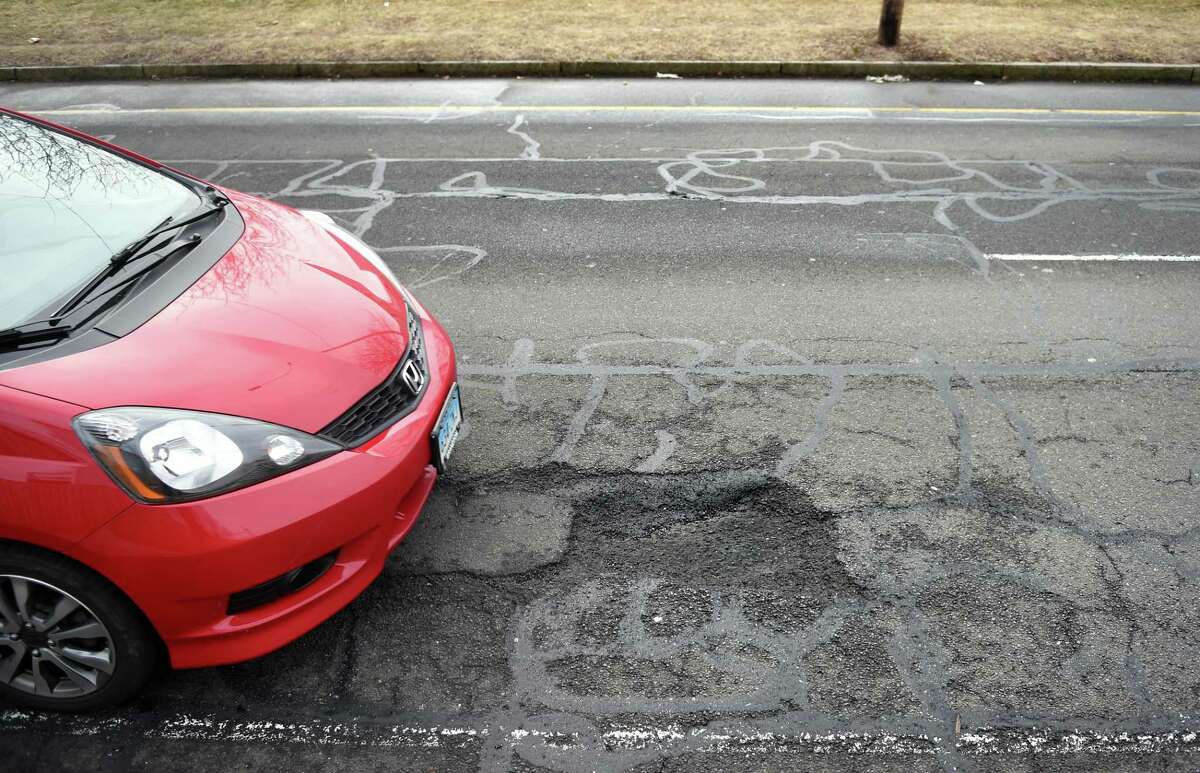 A car tries to avoid a pothole on North Frontage Road between Dwight and Orchard streets in New Haven on March 15, 2019.