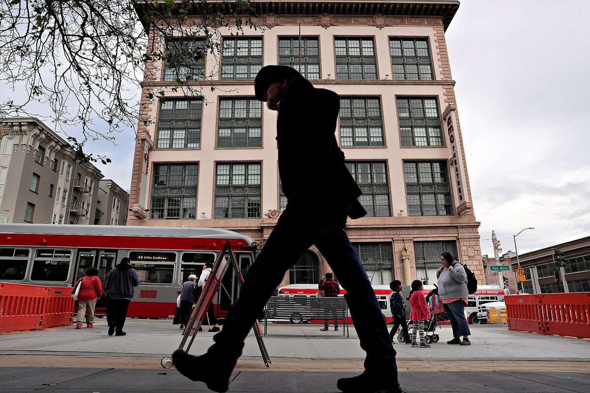 A man walks by a temporary bus platform in front of the old AMC Theater building on Van Ness Avenue in San Francisco, Calif., on Thursday, March 7, 2019. Morgan is a neighborhood activist who has been working on improving Van Ness for decades, and while California Pacific Medical Center has been recently completed, there are three developments that are stalled -- 1001 Van Ness, 1200 Van Ness, and the parking lot behind the Opal Motel.