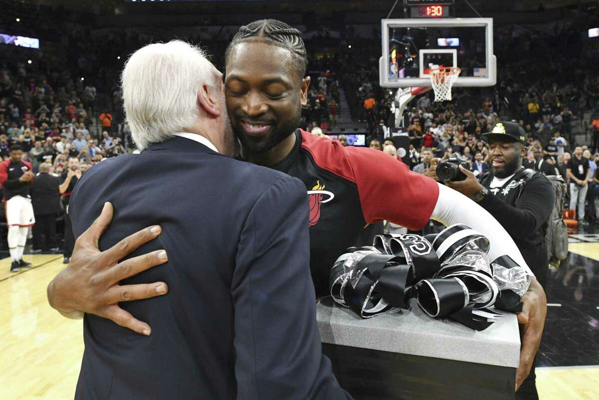 DeWayne Wade, veteran guard of the Miami heat, who is retiring at the end of the season, embraces San Antonio Spurs coach Gregg Popovich after receiving a gift before the teams' NBA game in the AT&T Center on Wednesday, March 20, 2019.