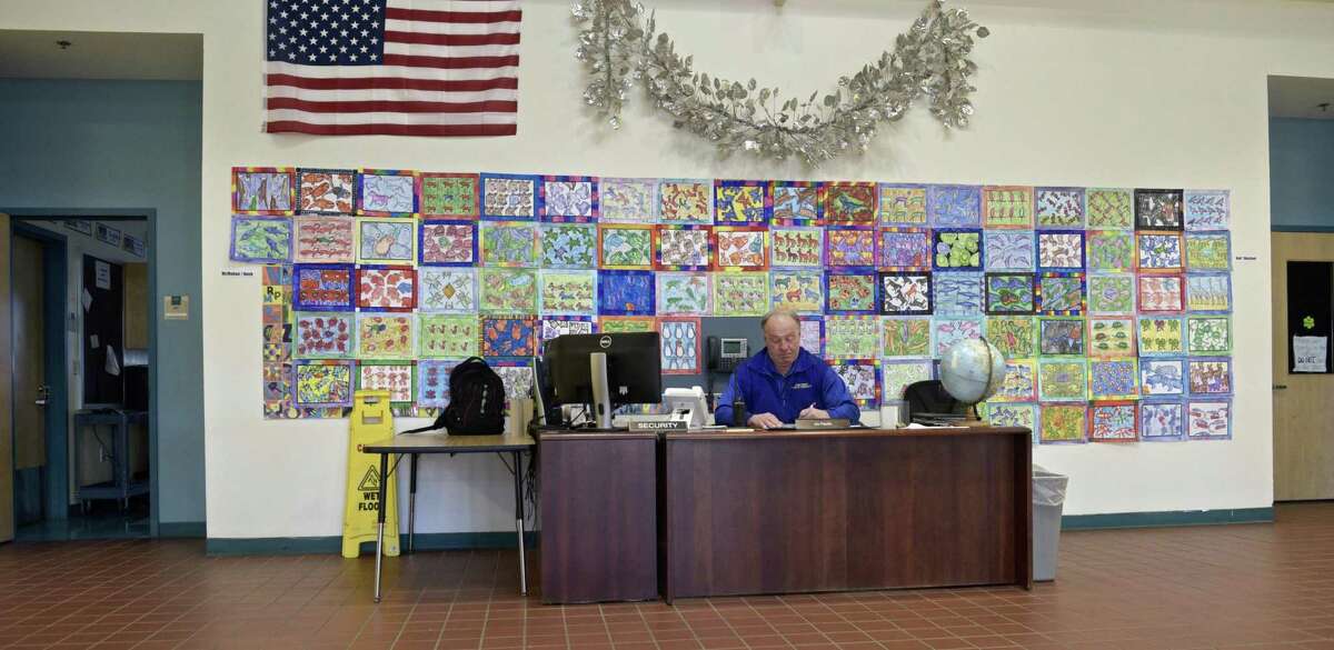 Jim Pacific, an armed school security guard, works at the security desk in the main entrance in Reed Intermediate School in Newtown on Tuesday.