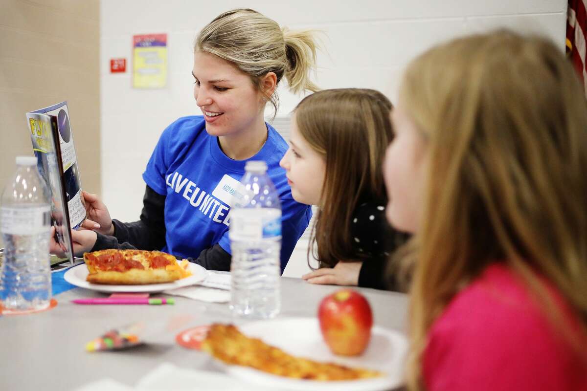 Kasey Harter, left, a volunteer with United Way of Midland County's Young Leaders United group, reads a book with Plymouth Elementary second graders Vivienne Jacobscarter, 8, center, and Cayla Oliver, 7, right, during a celebration of March being National Reading Month on Thursday, March 21, 2019 at the school. (Katy Kildee/kkildee@mdn.net)