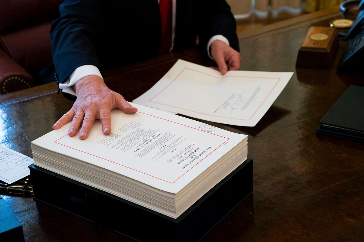 FILE -- President Donald Trump with the tax bill at a signing ceremony at the White House in Washington, Dec. 22, 2017. Polling shows those getting smaller refunds are less likely to view the tax overhaul favorably, even if their take-home pay grew. (Doug Mills/The New York Times)