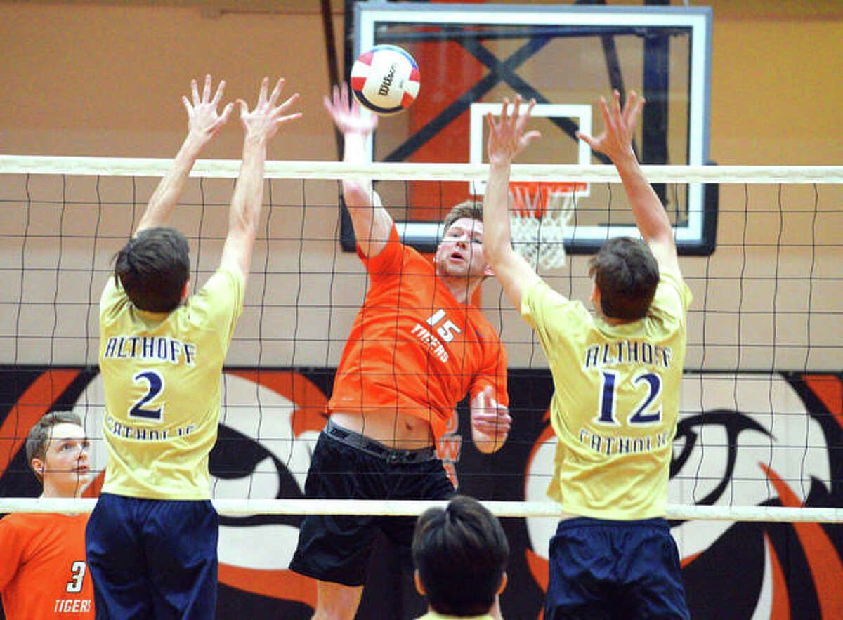 Edwardsville junior Daniel Pauk, middle, goes for a kill between two Belleville Althoff players during Thursday’s season opener at Lucco-Jackson Gymnasium.