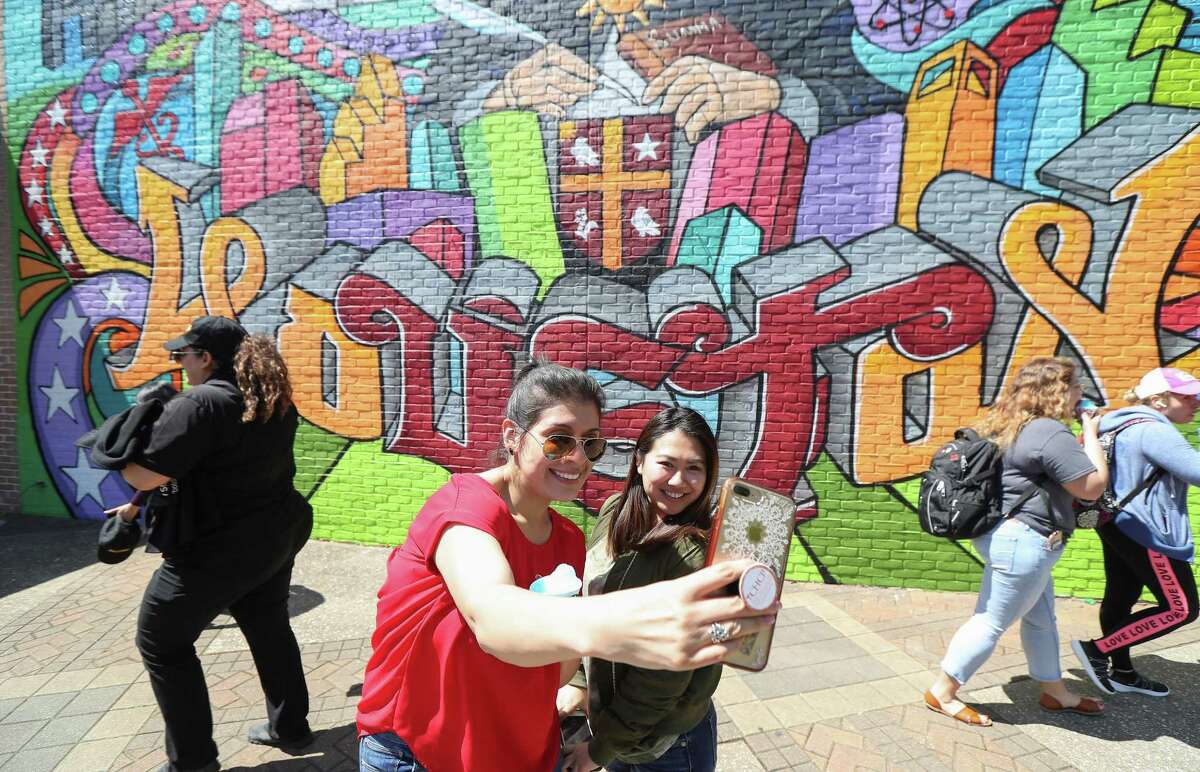 University of St. Thomas students Raiza Torres, left, and Heidi Chang attempt to take a photo in front of Gonzo247's first on-campus mural Thursday, March 21, 2019, in Houston. The large mural was painted by well-known graffiti artist Mario Figueroa, Jr., who goes by the moniker Gonzo247, depicts St. Thomas Aquinas, the Italian Catholic priest who inspired the university's name.