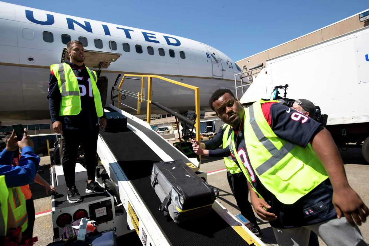 Houston Texans linebacker Dylan Cole (51) and defensive end Carlos Watkins (91) help load baggage aboard an United aircraft as the Texans players, cheerleaders and Toro visited with passengers and helped with some operations at George Bush Intercontinental Airport on Thursday, March 21, 2019, in Houston.