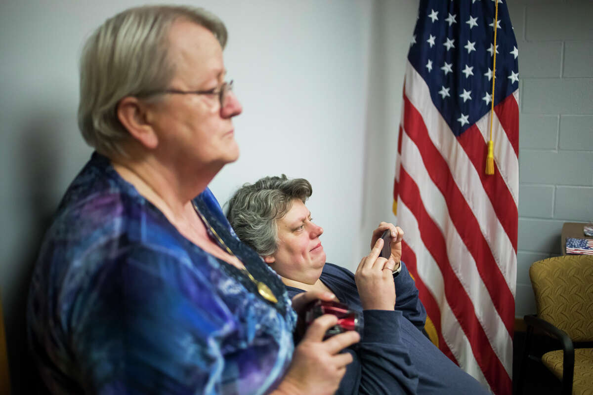 Hazel Webster of Sanford, left, and her daughter Kimberly Webster, right, take photos as U.S. Rep. John Moolenaar presents Hazel's husband and Kimberly's father, Dennis Webster, with the National Defense Service Medal and the Sharpshooter Badge with Rifle Bar on Thursday, March 21, 2019 in Moolenaar's office in Midland. Webster was also presented with honors on behalf of his father, David Webster, who served in the Army and the Navy during World War II. (Katy Kildee/kkildee@mdn.net)