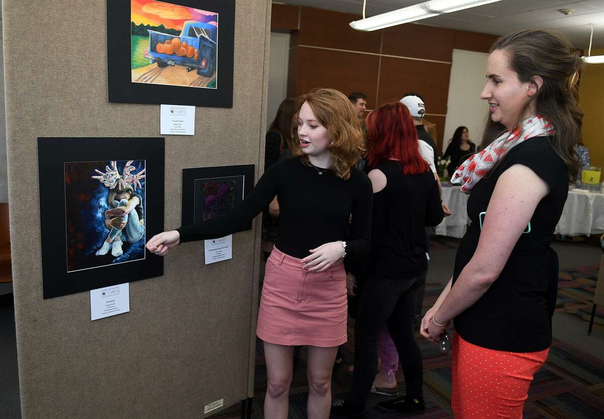 Kaitlyn Snyder, 17, left, a junior at Tomball High School, talks about her peice, entitled "Anxiety", with Tomball Memorial High School Art teacher Rachel Hooker during the grand opening and celebration of the Tomball Community Art Showcase at the Lone Star College-Tomball Community Library on March 21, 2019.