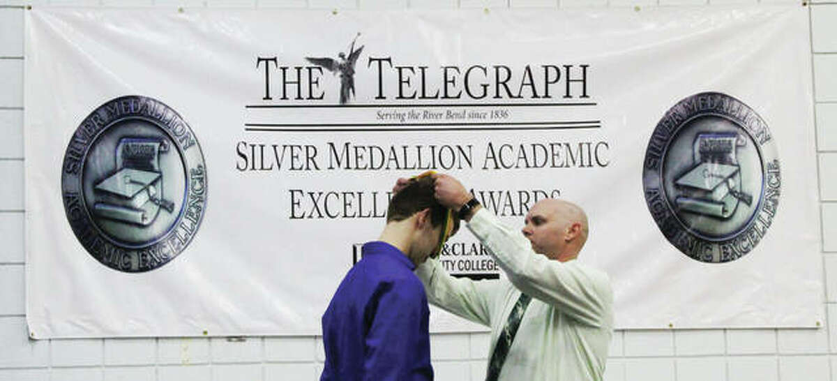 Joshua Jacobsen, a senor at Metro-East Lutheran High School, receives his silver medallion from Assistant Principal Rob Stock at the 31st annual Silver Medallion Academic Excellence Awards Banquet Thursday at L&C.