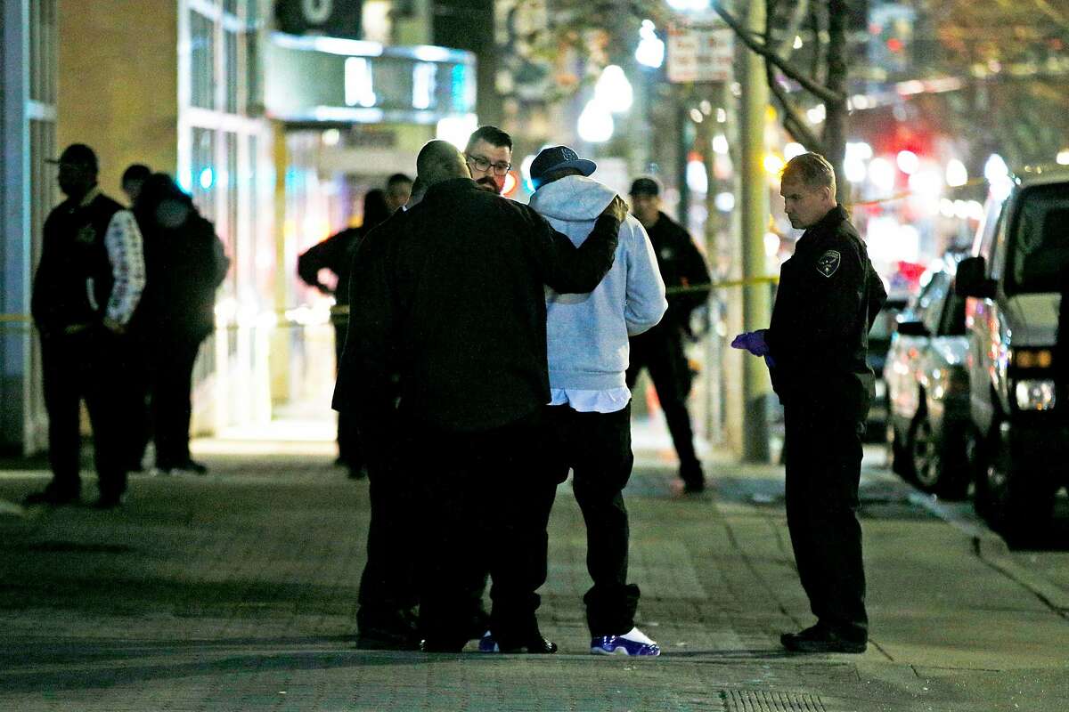 A man is comforted as police investigate a shooting along Fillmore Street on Saturday, March 23, 2019, in San Francisco, Calif. Police said that one person is dead and another three injured in the shooting.