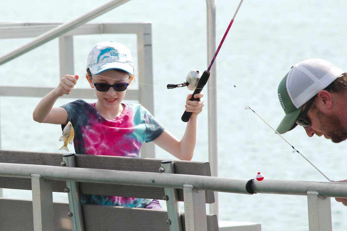Payton Oliver pulls in a sunfish while fishing with her father Eric Oliver at Lake Friendswood Sunday, Mar. 24.