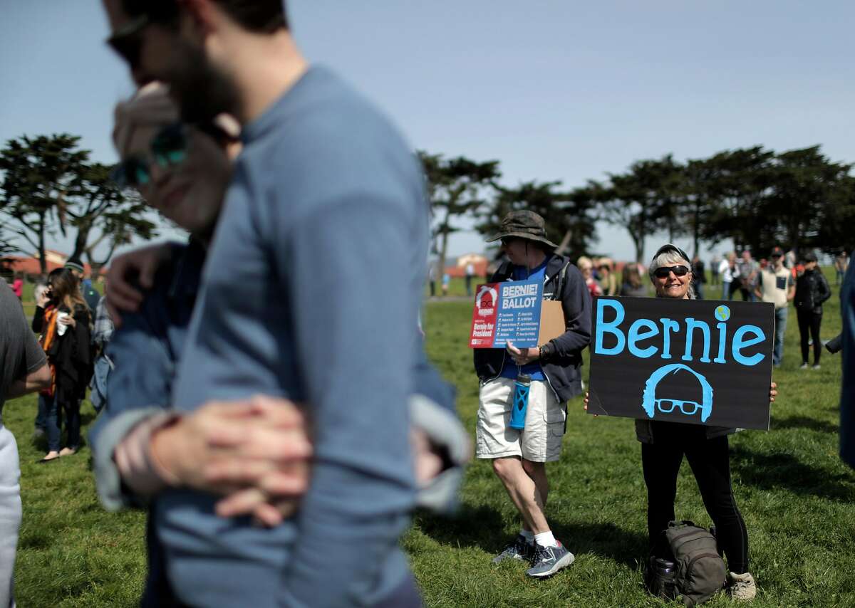 Isabella Wilk, right, and Scott Sammler, left, of Alameda hold signs in support of Democratic presidential candidate Sen. Bernie Sanders, I-Vt., before a rally at Great Meadow Park at Fort Mason in San Francisco, Calif., on Sunday, March 24, 2019.